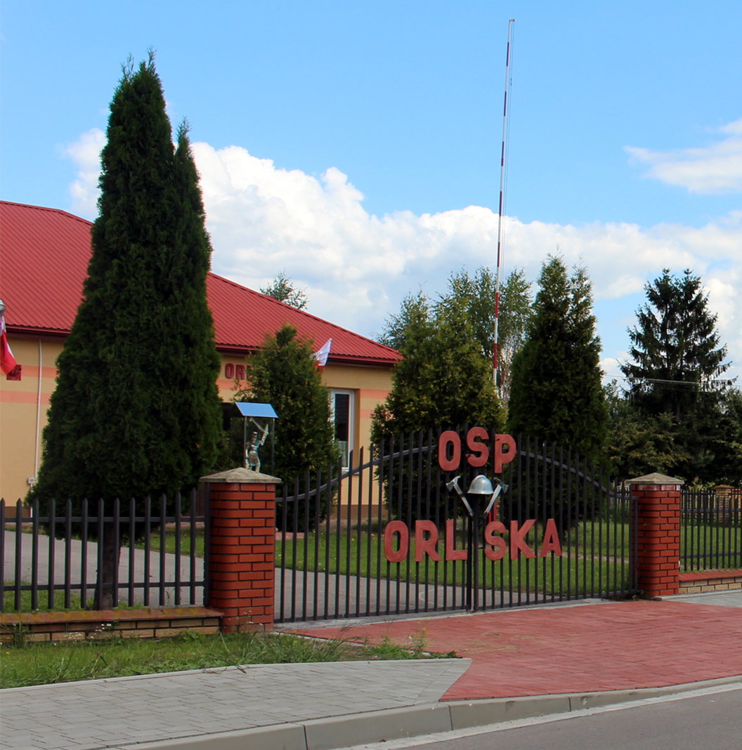 Orliska - siedziba OSP. Widok na bramę wjazdową w tle budynek strażacki