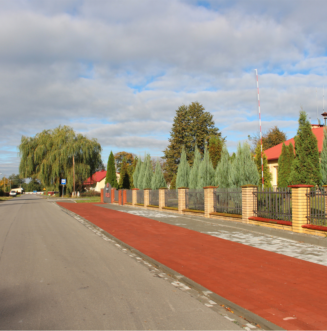 Orliska - główna drogra prowadząca przez miejscowość, obok chodnik a po prawej stronie widać fragment budynku - remizy OSP
